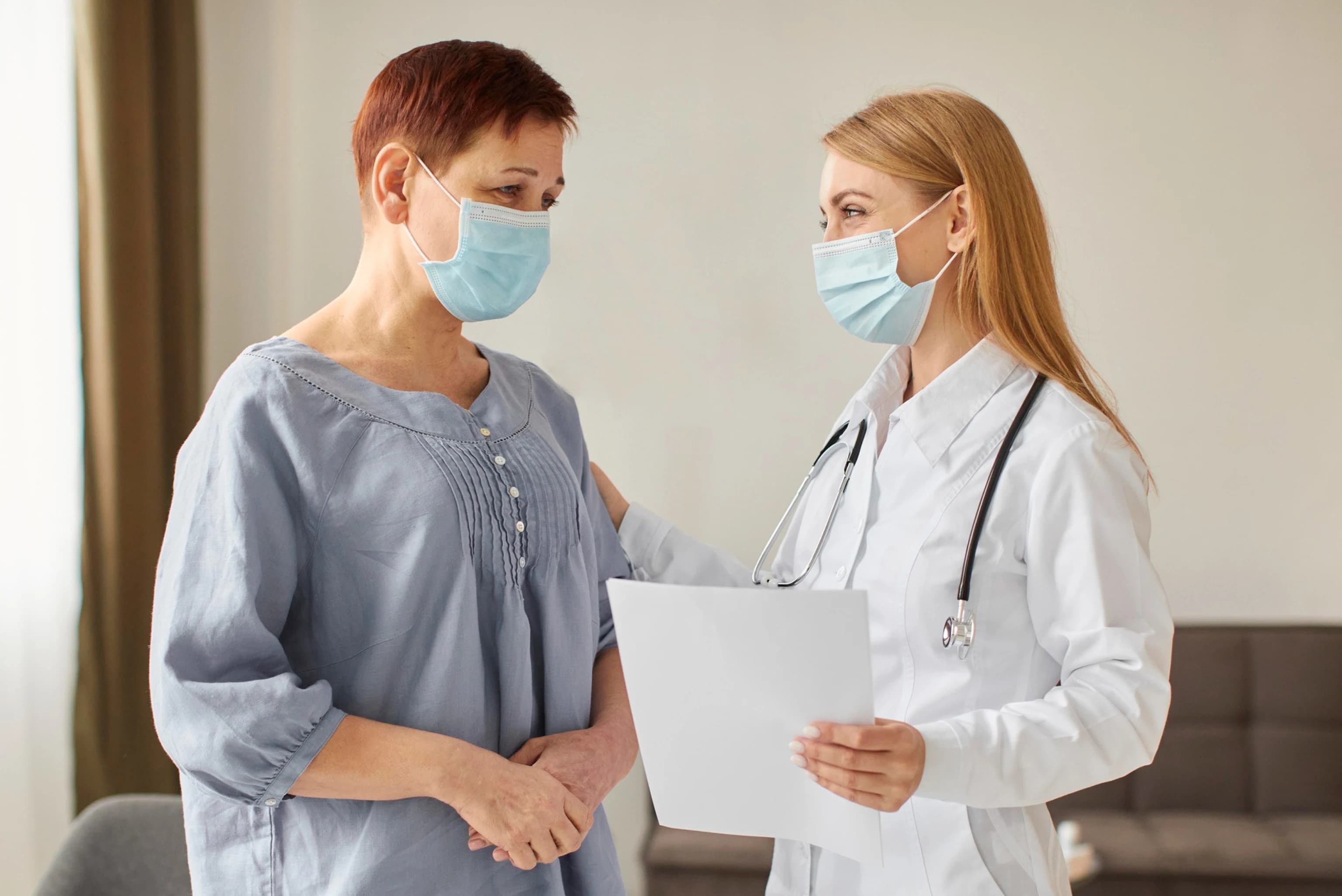 Physician in a white coat talking with a patient during an in-home visit