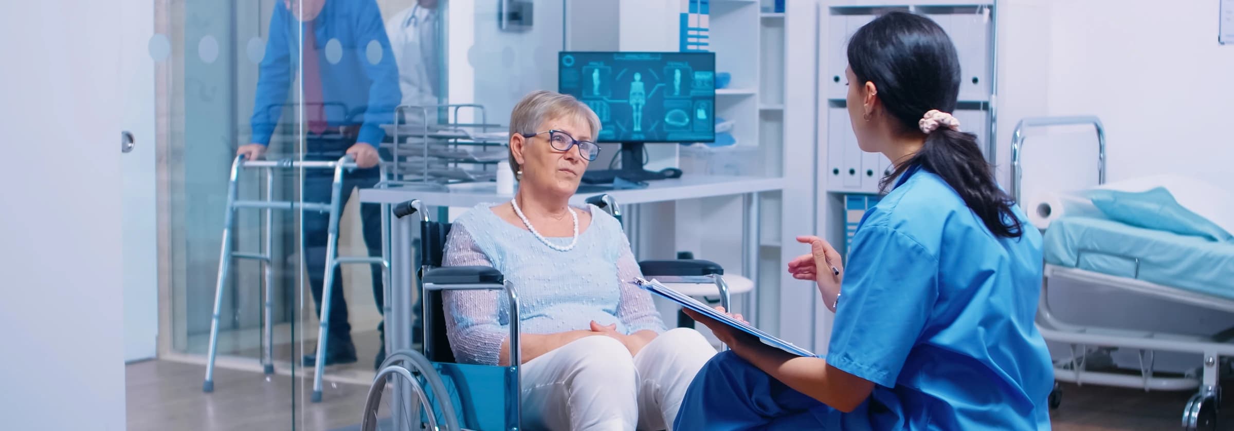 Nurse with a clipboard talking with an elderly patient in a wheelchair