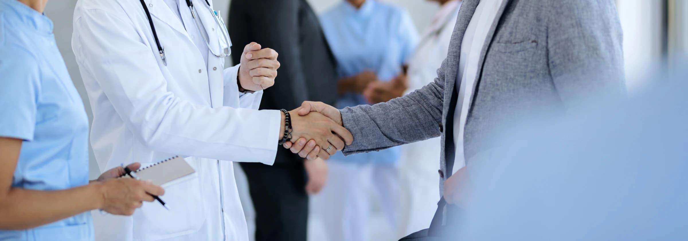 Doctor in a white coat shaking hands with a healthcare administrator