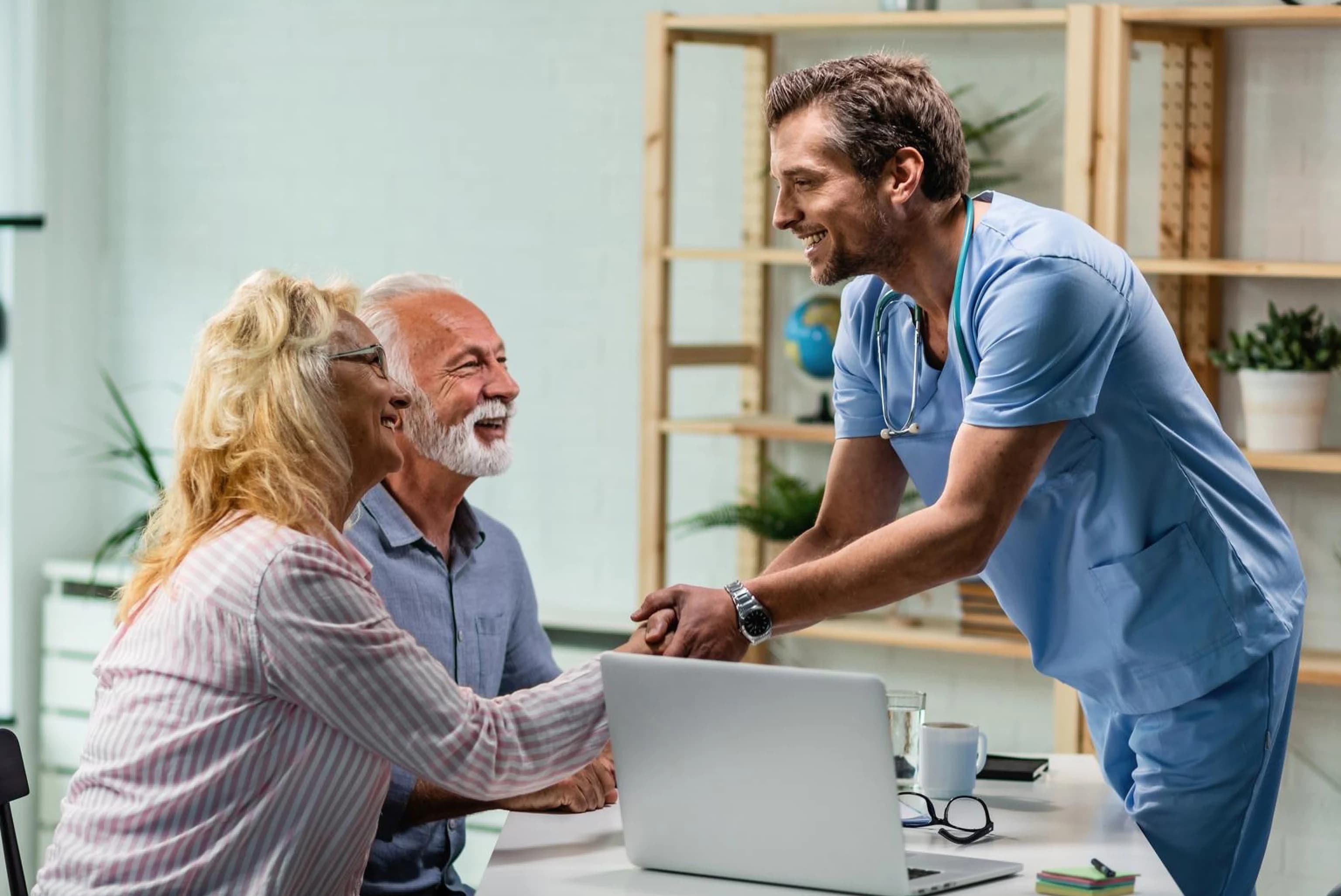 Smiling healthcare professional shaking hands with a couple during a consultation